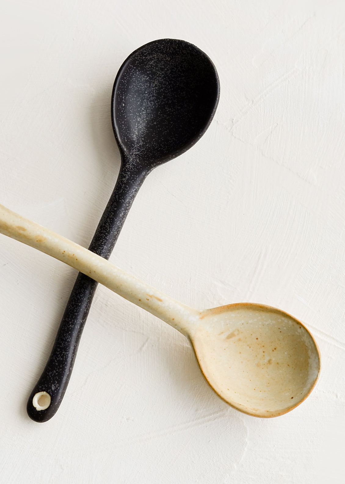 Ceramic spoons, one in black, one in natural.