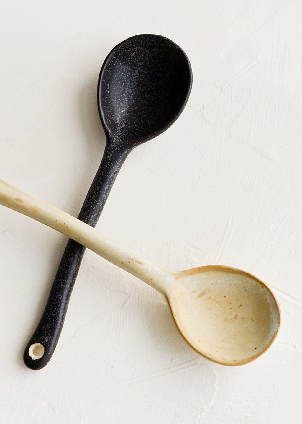 1: Ceramic spoons, one in black, one in natural.