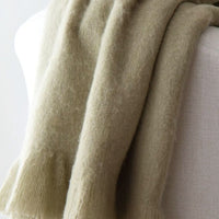 Sage: A sage green mohair throw blanket draped over a chair.