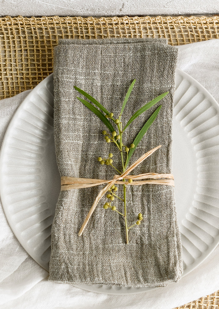 A pair of dusty sage green slub-textured woven napkins.