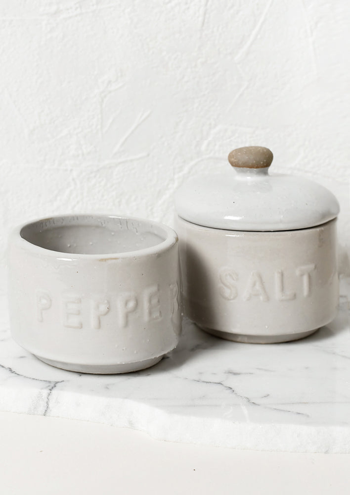 Stackable white ceramic salt and pepper jar with lid.