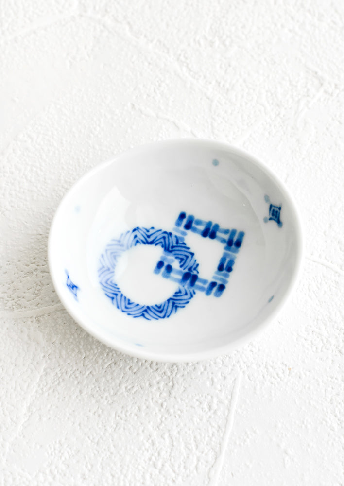 A round ceramic trinket dish with abstract pattern in blue.