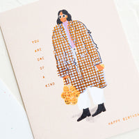 1: A greeting card with image of woman wearing baggy coat, text reads "You are one of a kind, happy birthday".
