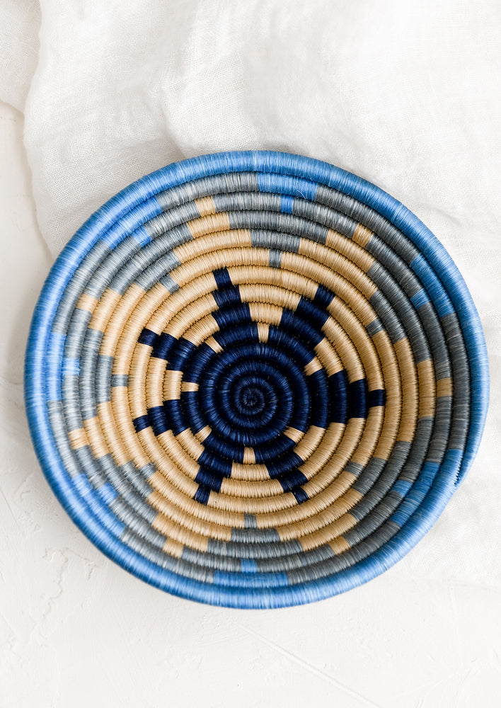 A blue and tan woven sweetgrass catchall with star pattern.