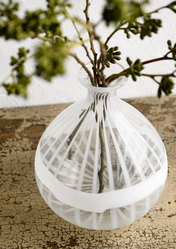 A clear balloon shaped glass vase with white stripe banding.