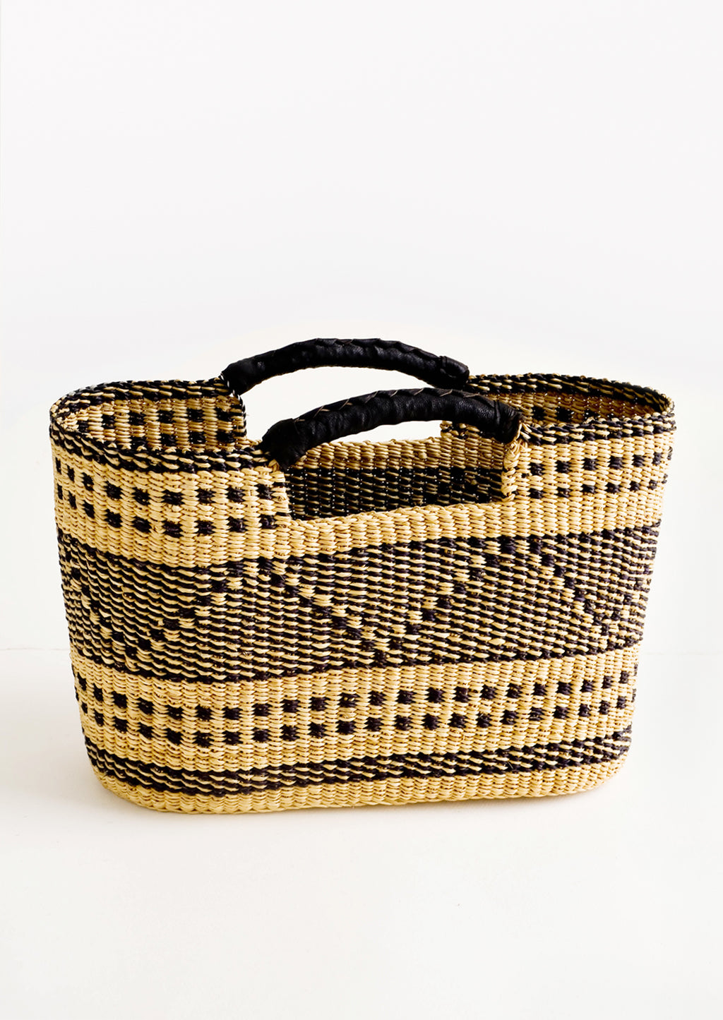 1: Woven tote made from natural and black dried grass, with geometric design and leather cutout handles