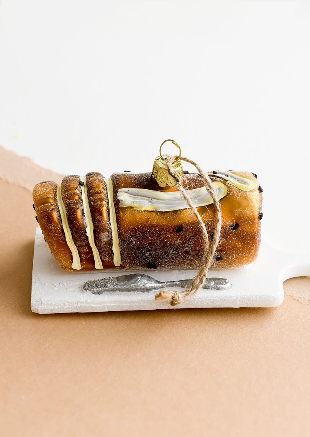 2: A decorative holiday ornament in shape of loaf of banana bread on platter.