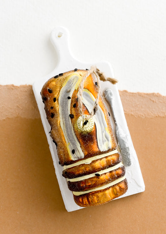 A decorative holiday ornament in shape of loaf of banana bread on platter.