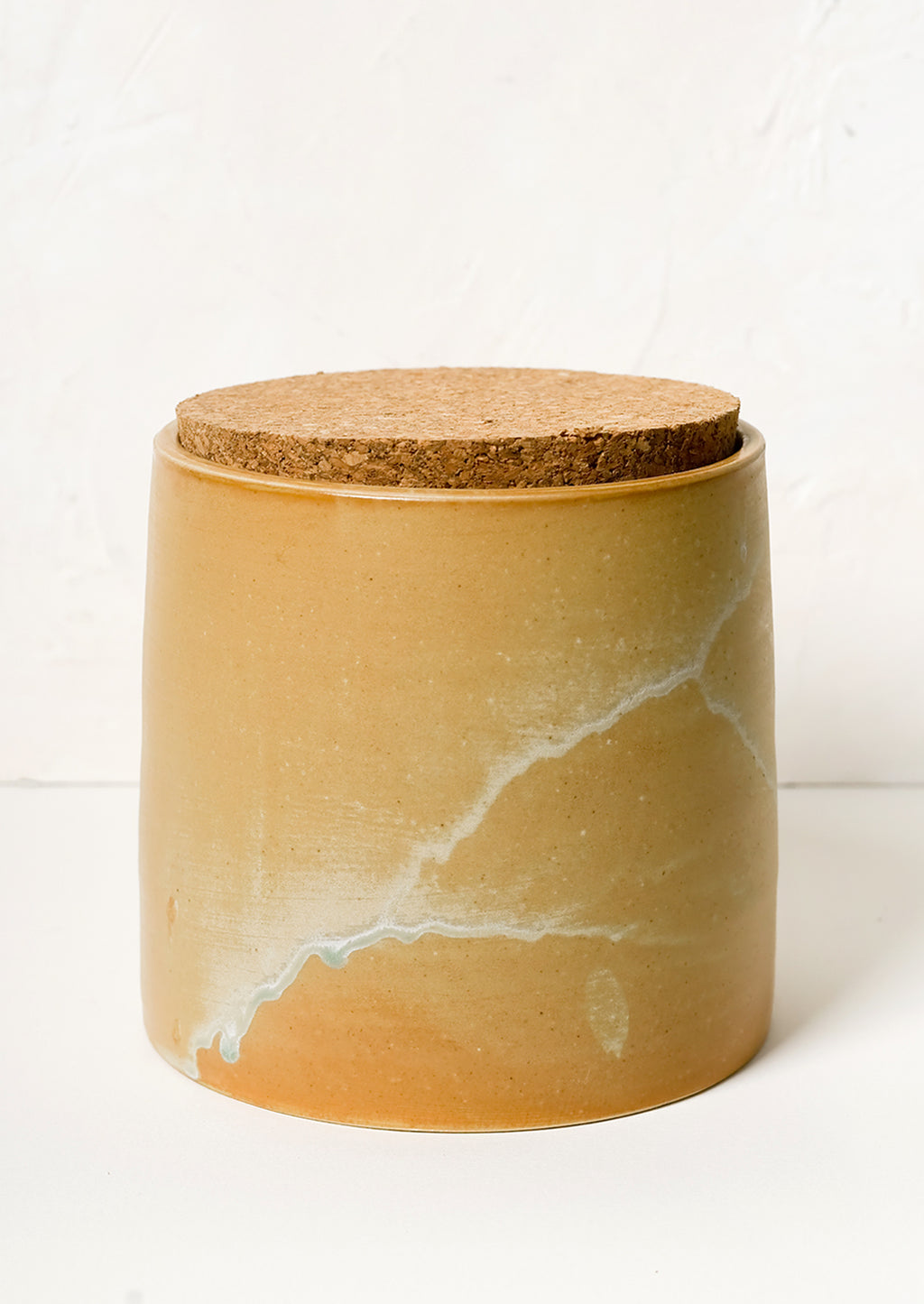 1: A ceramic storage jar in caramel glaze with cork lid.