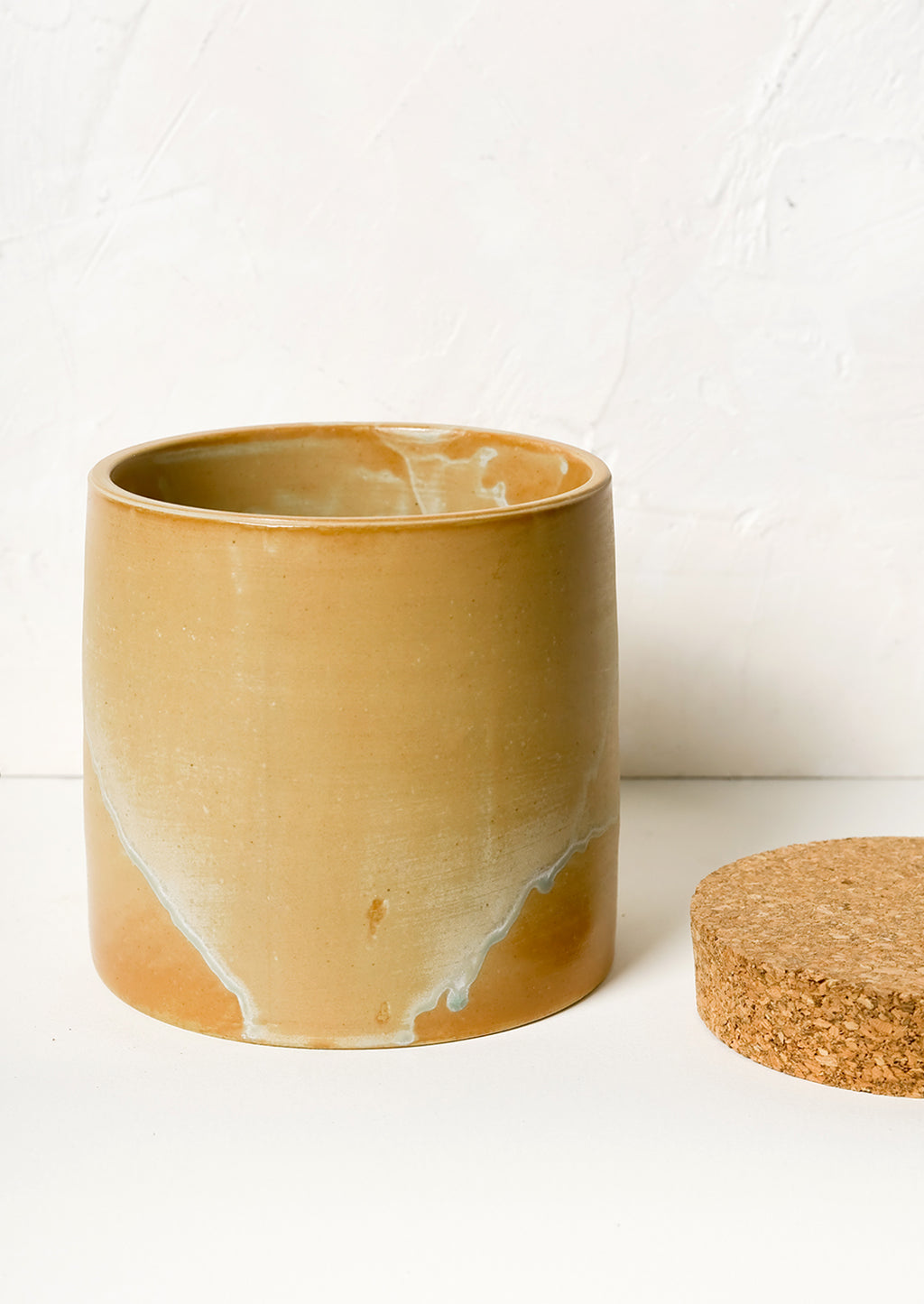 2: A ceramic storage jar in caramel glaze with cork lid.