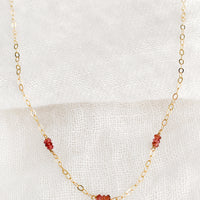 Garnet: A delicate gold chain necklace with garnet beaded stations.