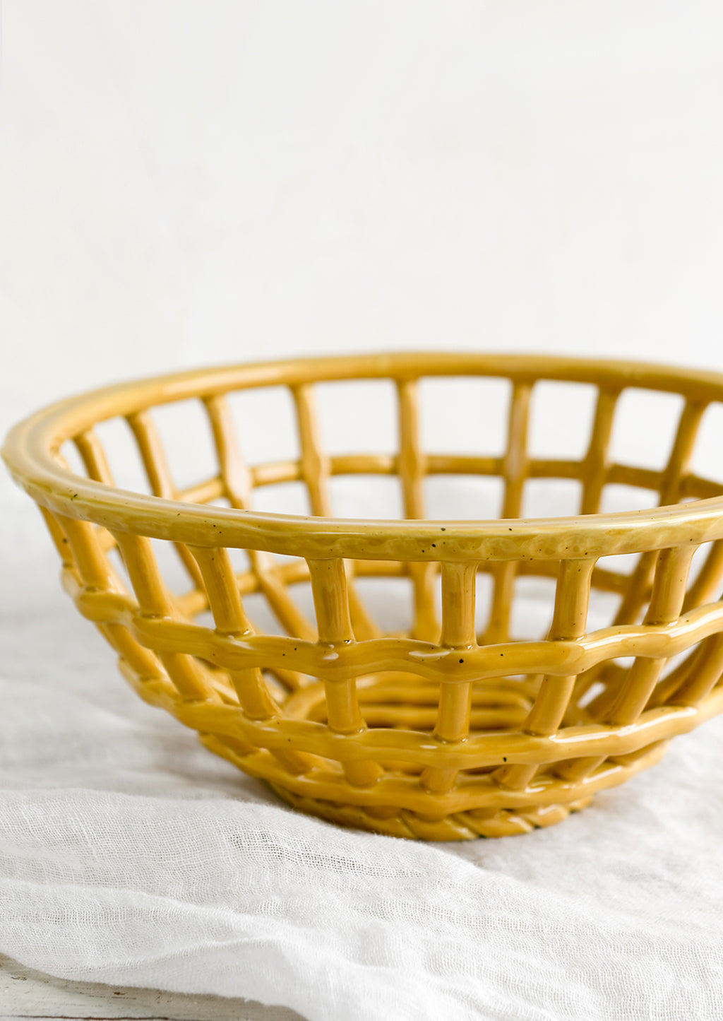 2: An open weave bowl made from mustard-colored ceramic.