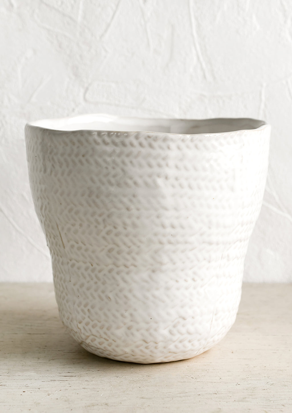 2: A white ceramic planter with basket shape and texture.