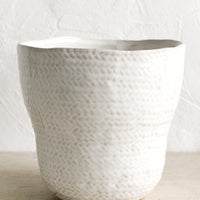2: A white ceramic planter with basket shape and texture.