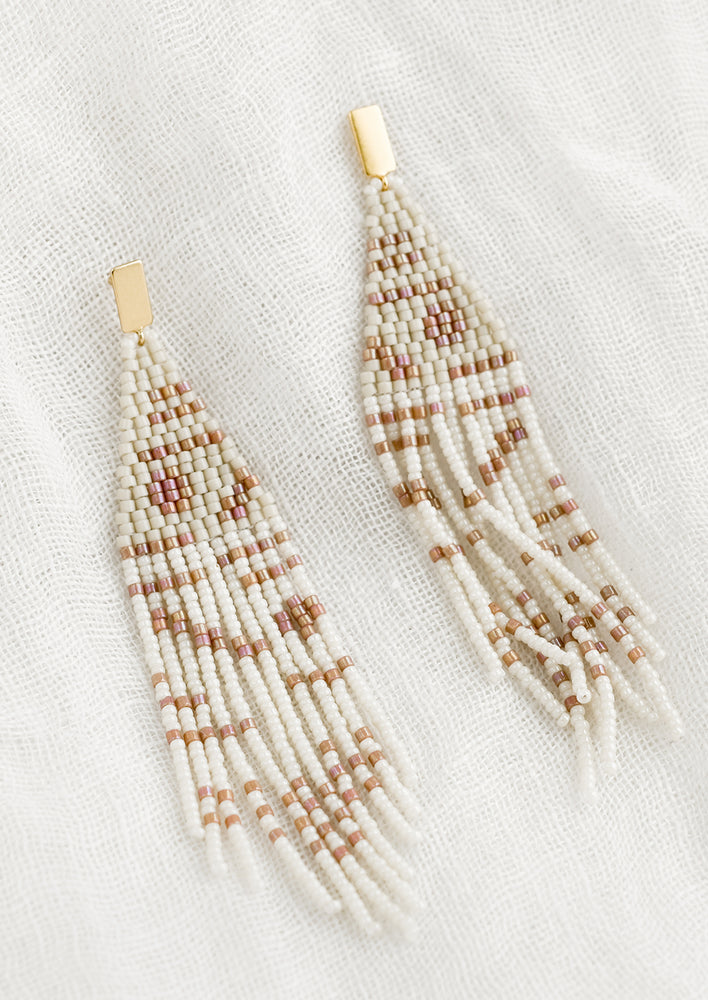 A pair of beaded earrings with geometric pattern in beige and white.