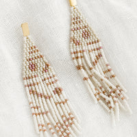 Linen Multi: A pair of beaded earrings with geometric pattern in beige and white.