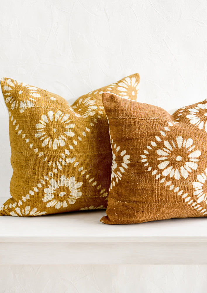 2: Mustard and brown mudcloth pillows with white floral motif.