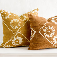 2: Mustard and brown mudcloth pillows with white floral motif.