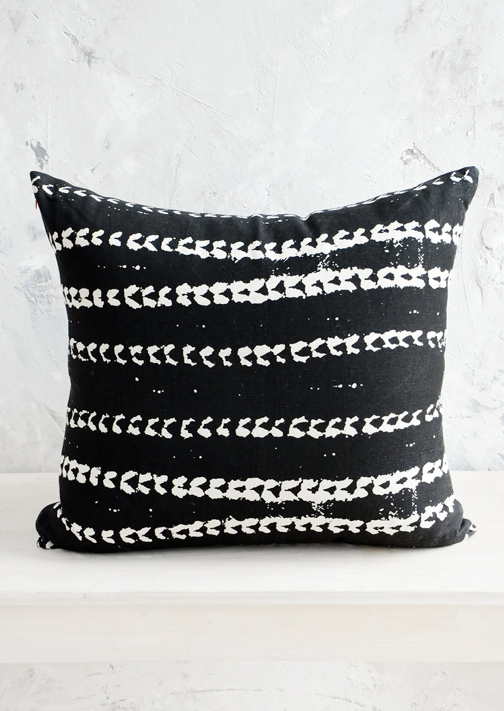 Black / White: Square throw pillow in black linen with horizontal batik print stripe pattern in white.