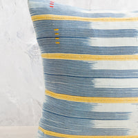 2: A square throw pillow in vintage African baule indigo ikat fabric with yellow accents.