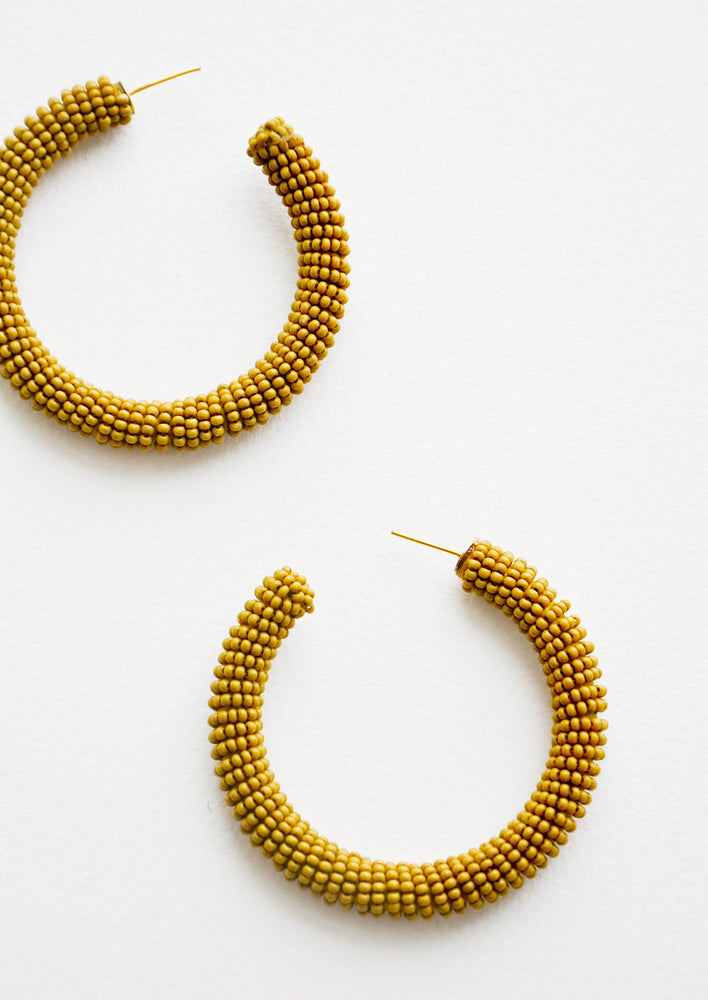 Thick hoop earrings of yellow-green colored glass beads.