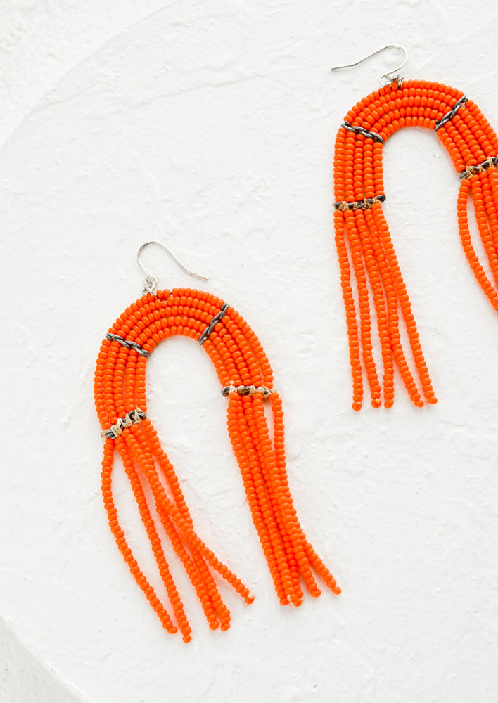 Arch shaped beaded earrings with fringed silhouette in flame orange.