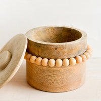2: A round wooden storage box with lid and wooden beaded detailing.