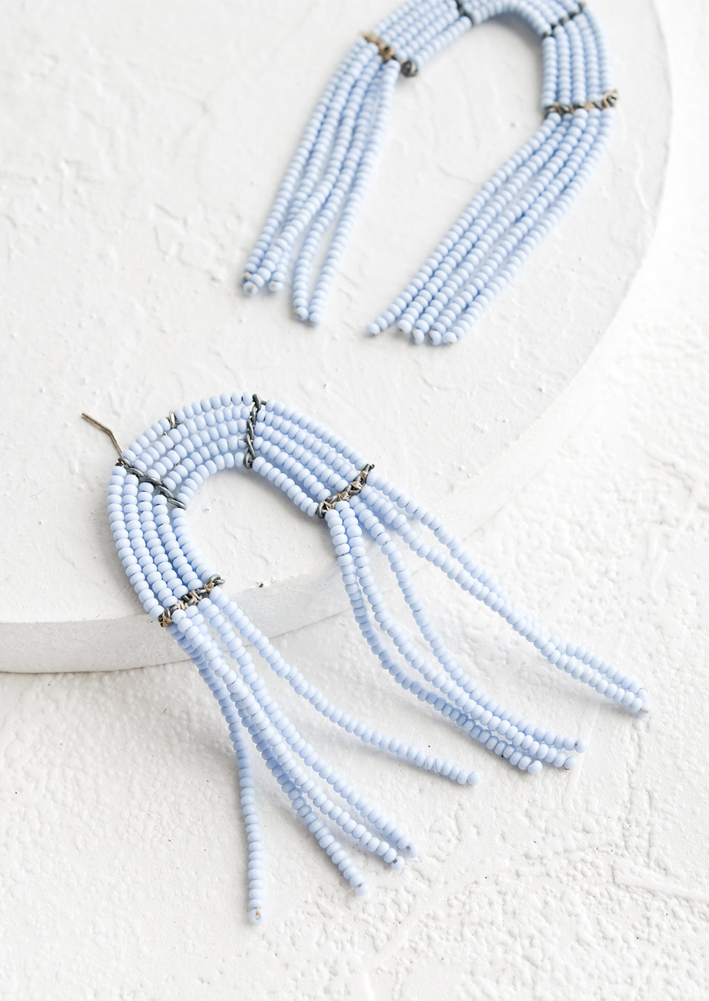 Periwinkle: Arch shaped beaded earrings with fringed silhouette in periwinkle.