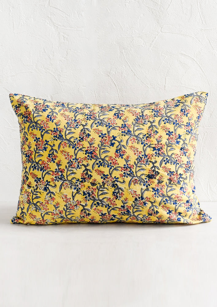 A block printed lumbar pillow in yellow with blue and pink floral print.