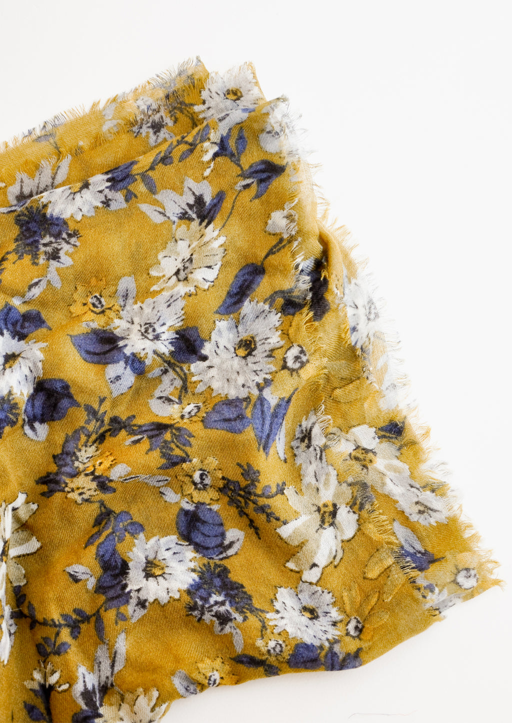 Green Ochre: Close up shot of scarf with dark yellow background and multi-colored blue and white floral pattern 