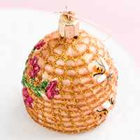 2: A glass ornament in shape of beehive with pink flowers.