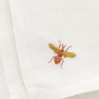 2: Embroidered bee on white linen.