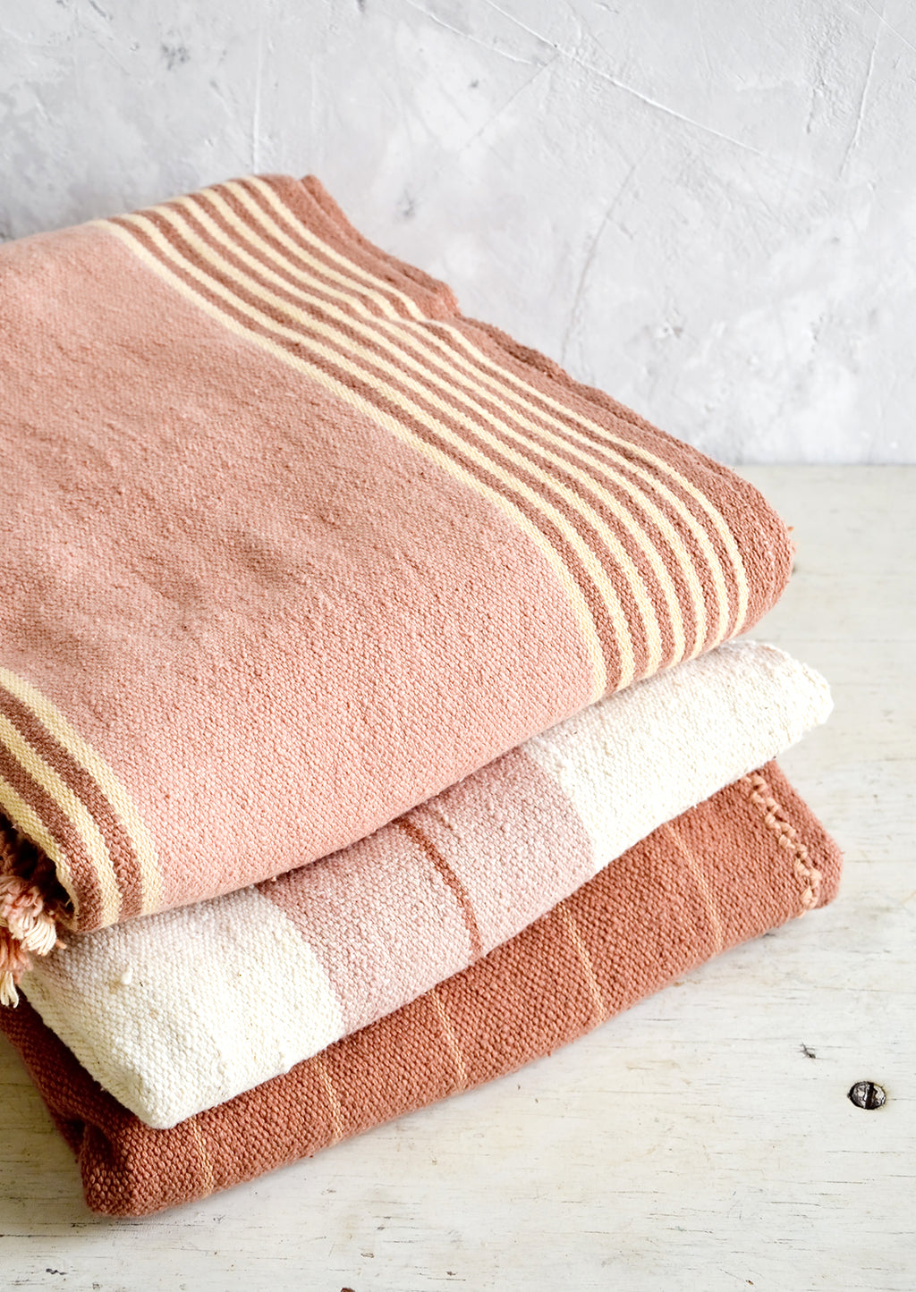 3: Stack of naturally colored cotton throws in pink, cream and terracotta