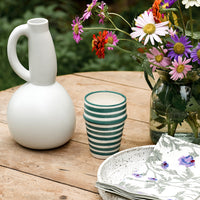 6: A table setting with pitcher, cup and flowers.