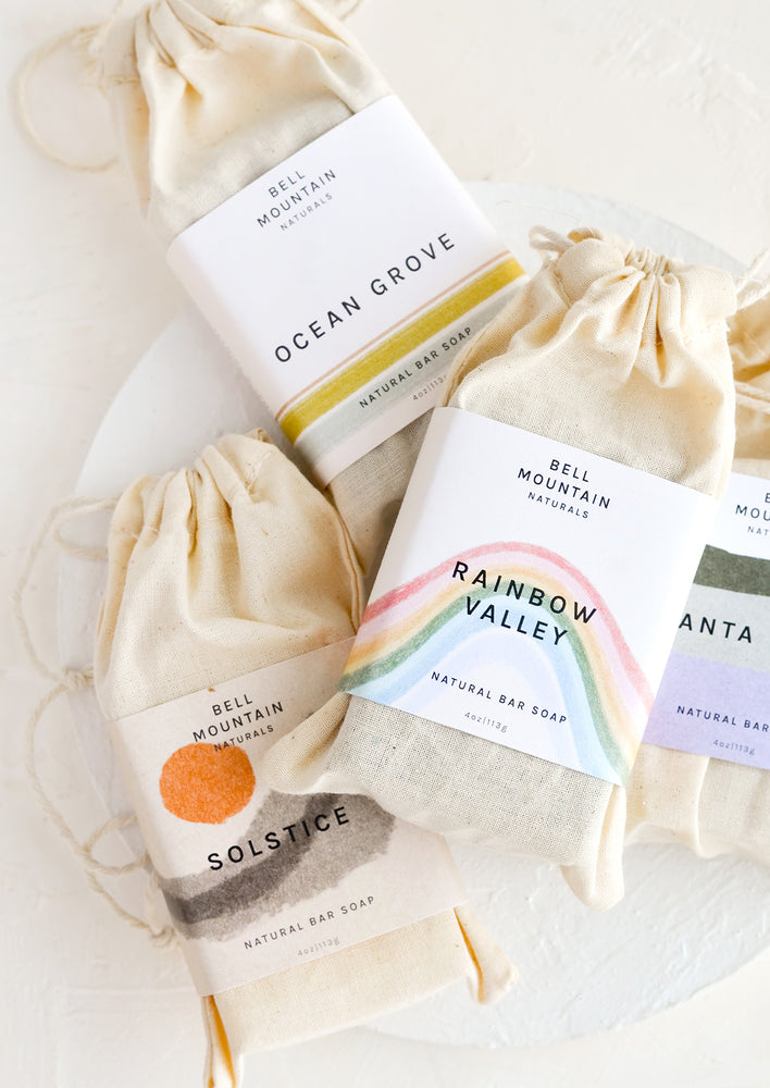 1: A stack of bar soaps in labeled muslin pouches.
