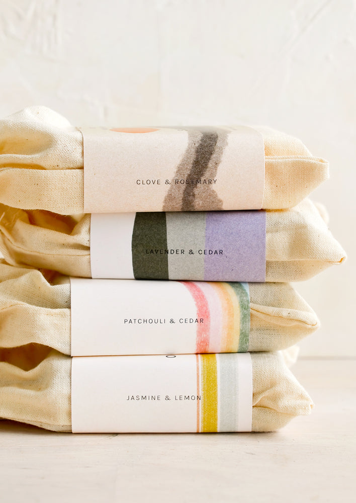 A stack of bar soaps in labeled muslin pouches.