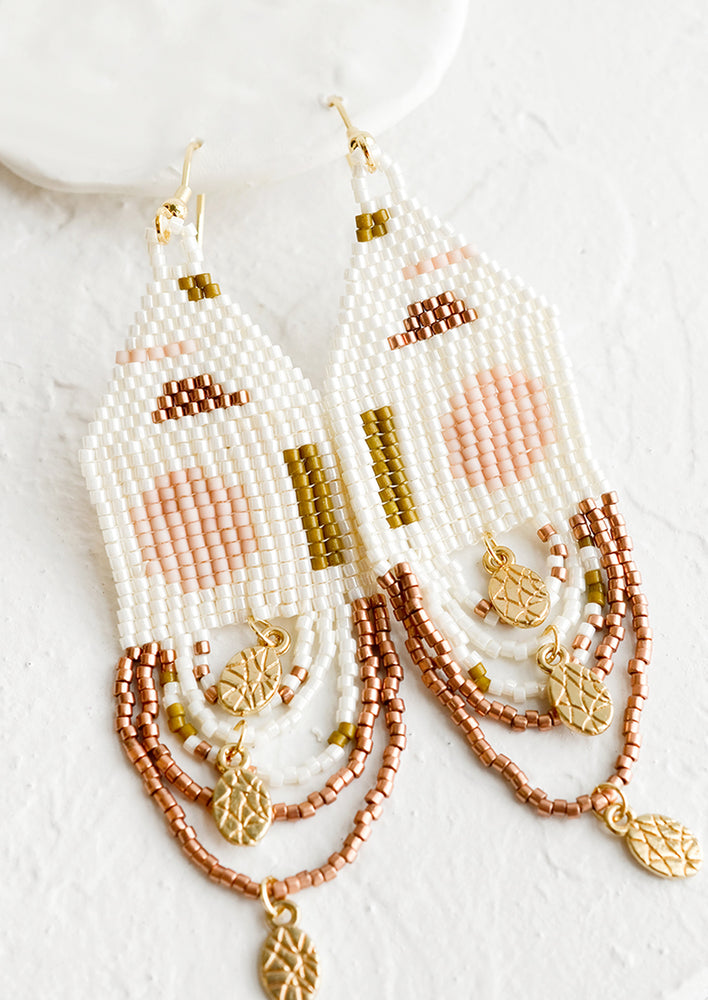 1: Beaded earrings with geometric pattern and gold charms on looped bottom strands.