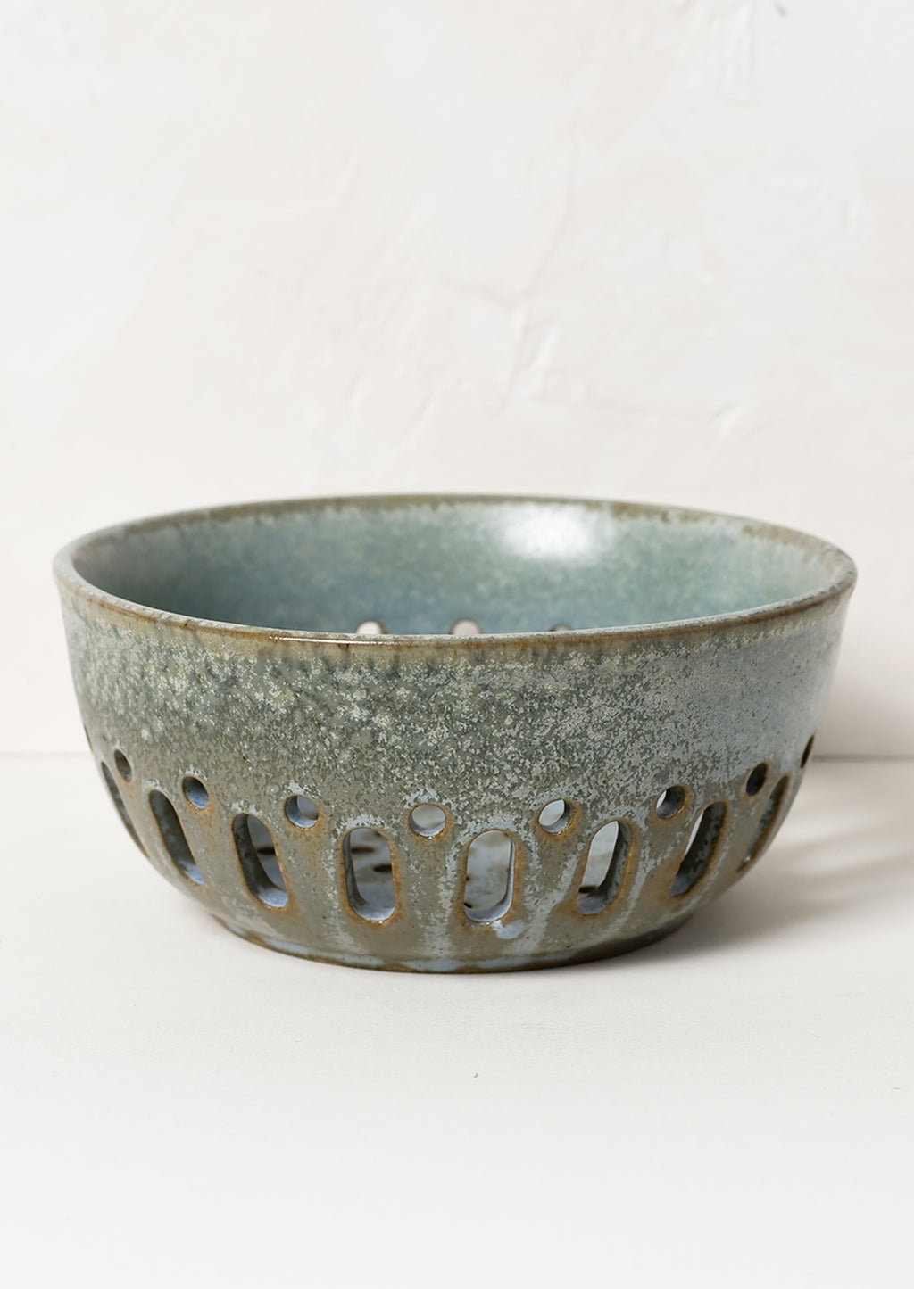 3: A ceramic berry colander in mottled blue green glaze.