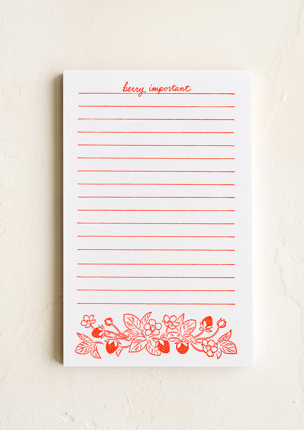 1: A white letterpress printed notepad with red lines and berry print.