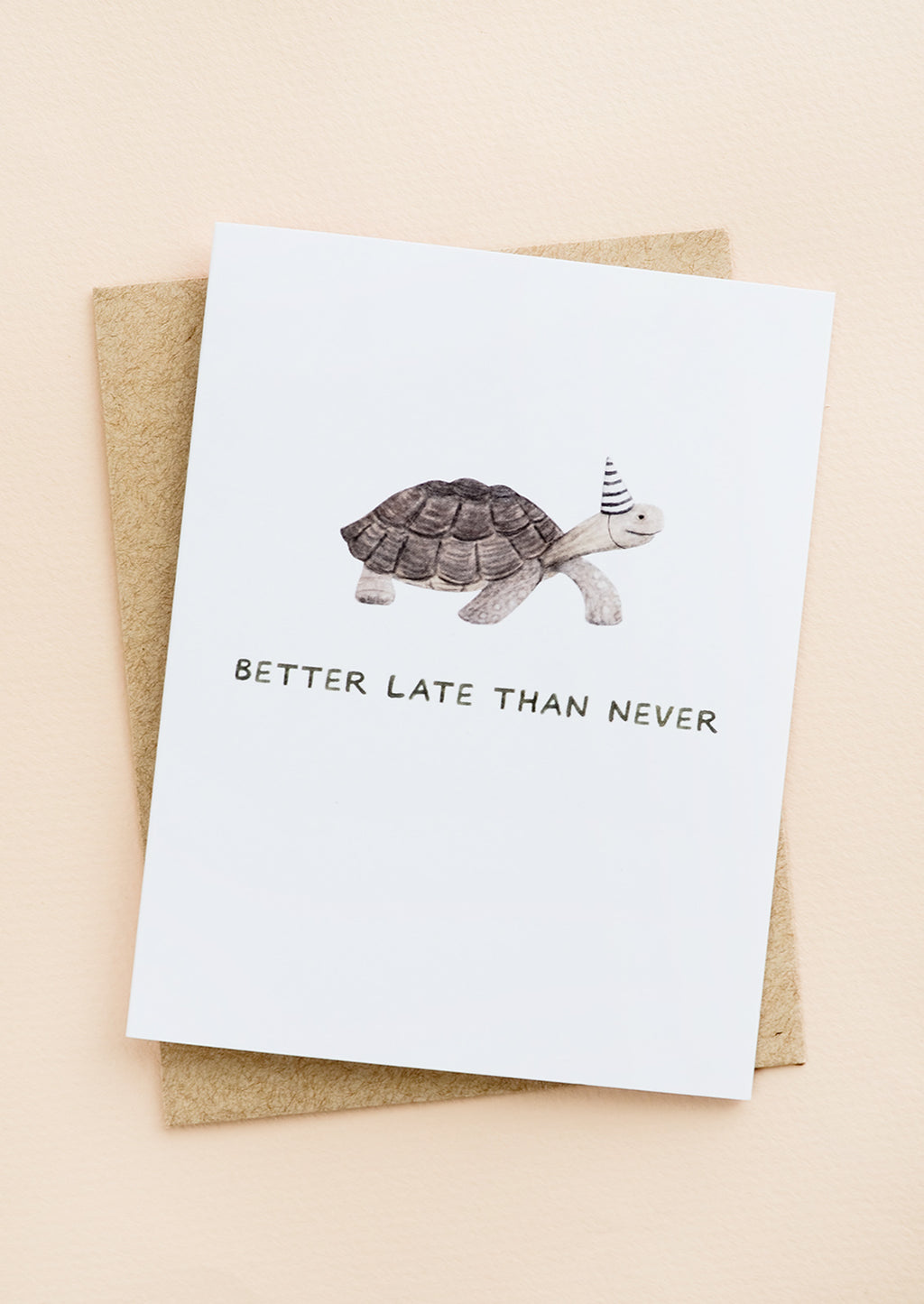 1: A greeting card with illustration of a tortoise in a party hat, text underneath reads "Better late than never".