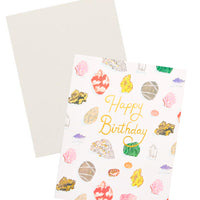3: Notecard with colorful drawings of gems and minerals and the text "Happy Birthday" in gold foil, with white envelope.