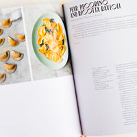 2: A hardcover cookbook open to a page with a recipe for ravioli.