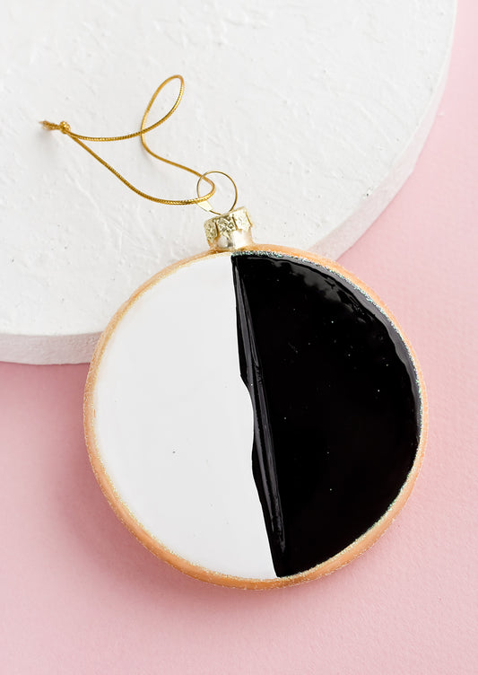 A decorative holiday ornament in the shape of a black & white cookie.