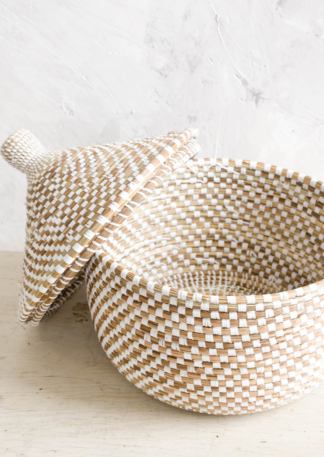 Woven storage basket made from natural grass with white checkered pattern