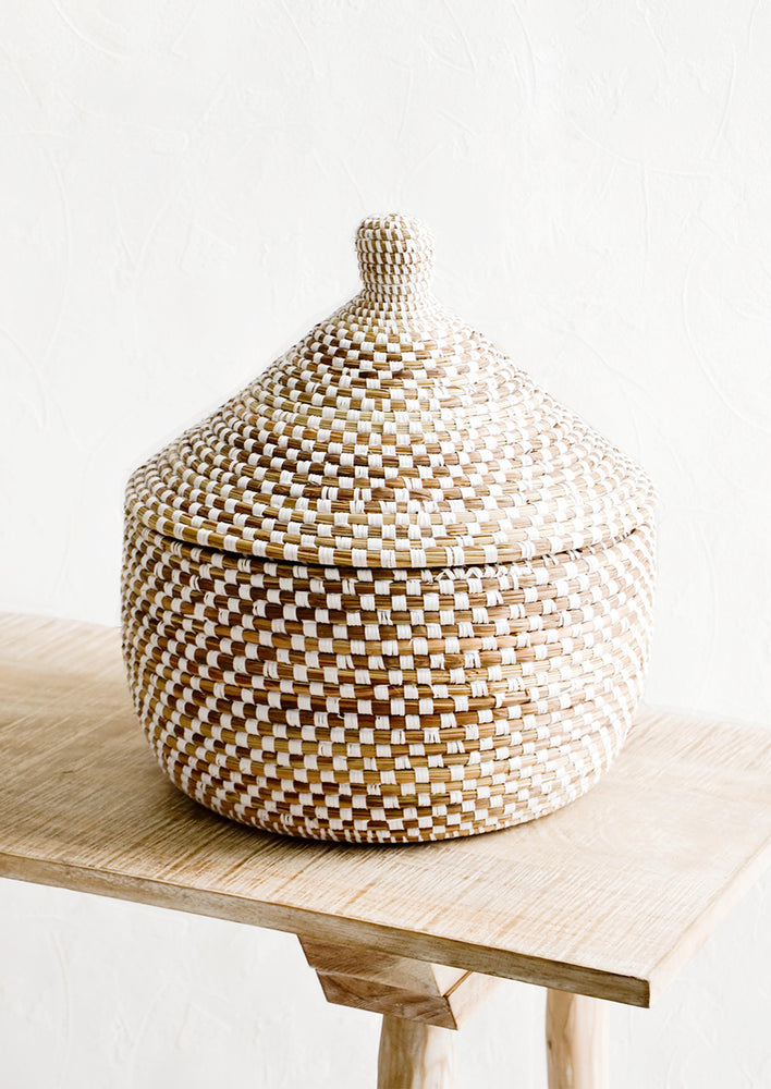 Lidded storage basket made from natural grass with white checkered pattern