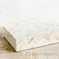 1: A rectangular storage box in cream colored herringbone pattern.
