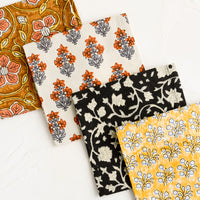 1: Four square fabric cocktail napkins in assorted colors and patterns.