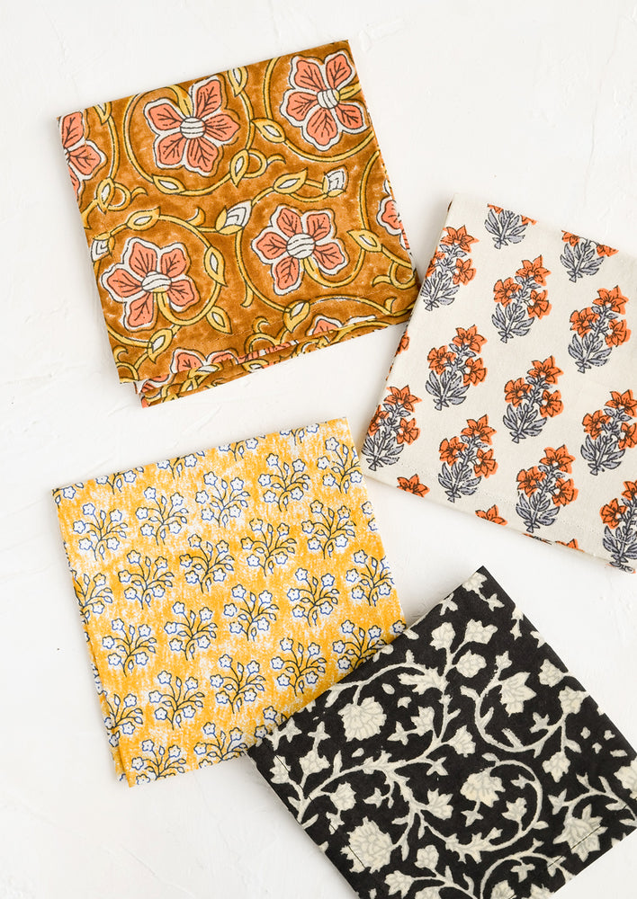 Four square fabric cocktail napkins in assorted colors and patterns.