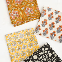 2: Four square fabric cocktail napkins in assorted colors and patterns.