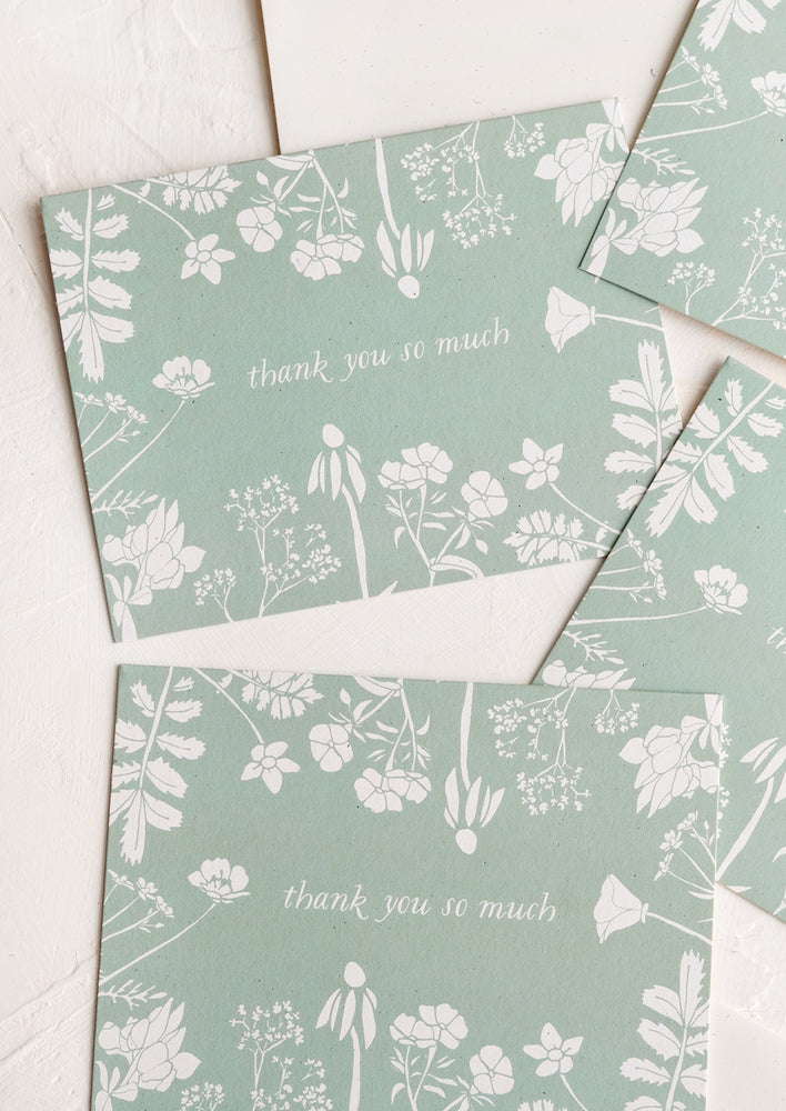A set of identical thank you cards with mint and white floral design.